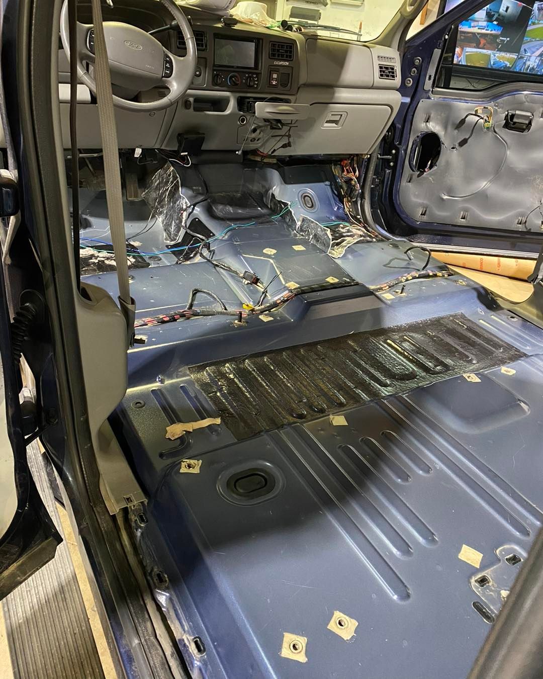 Car interior stripped bare after crash, with deployed airbags and removed floor panels.