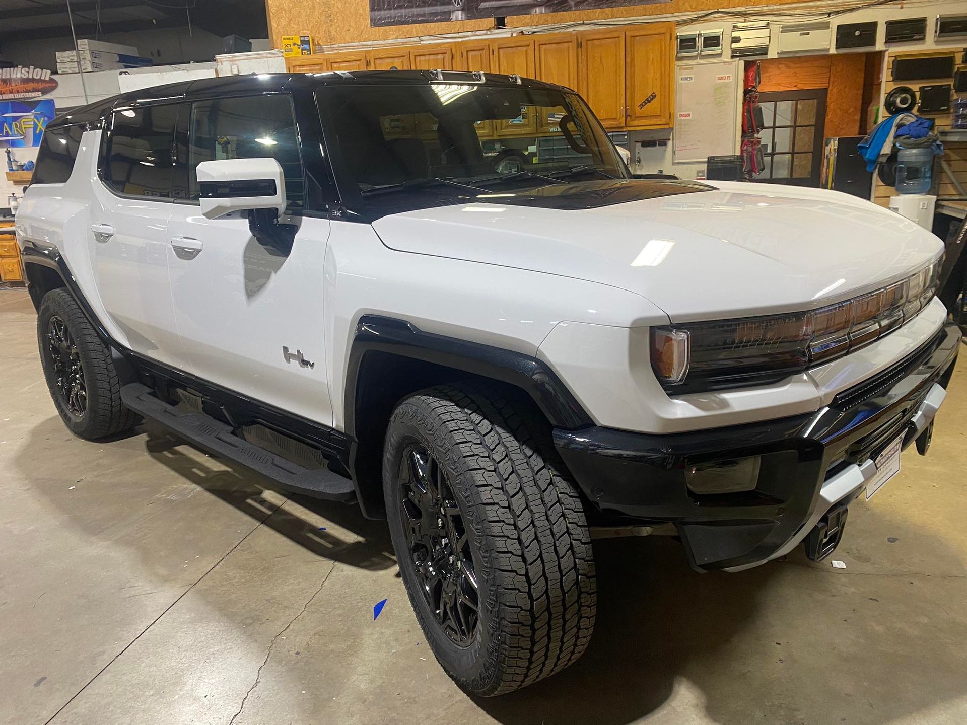 White off-road SUV in a workshop, shown from the front-left side with black trim and large tires.