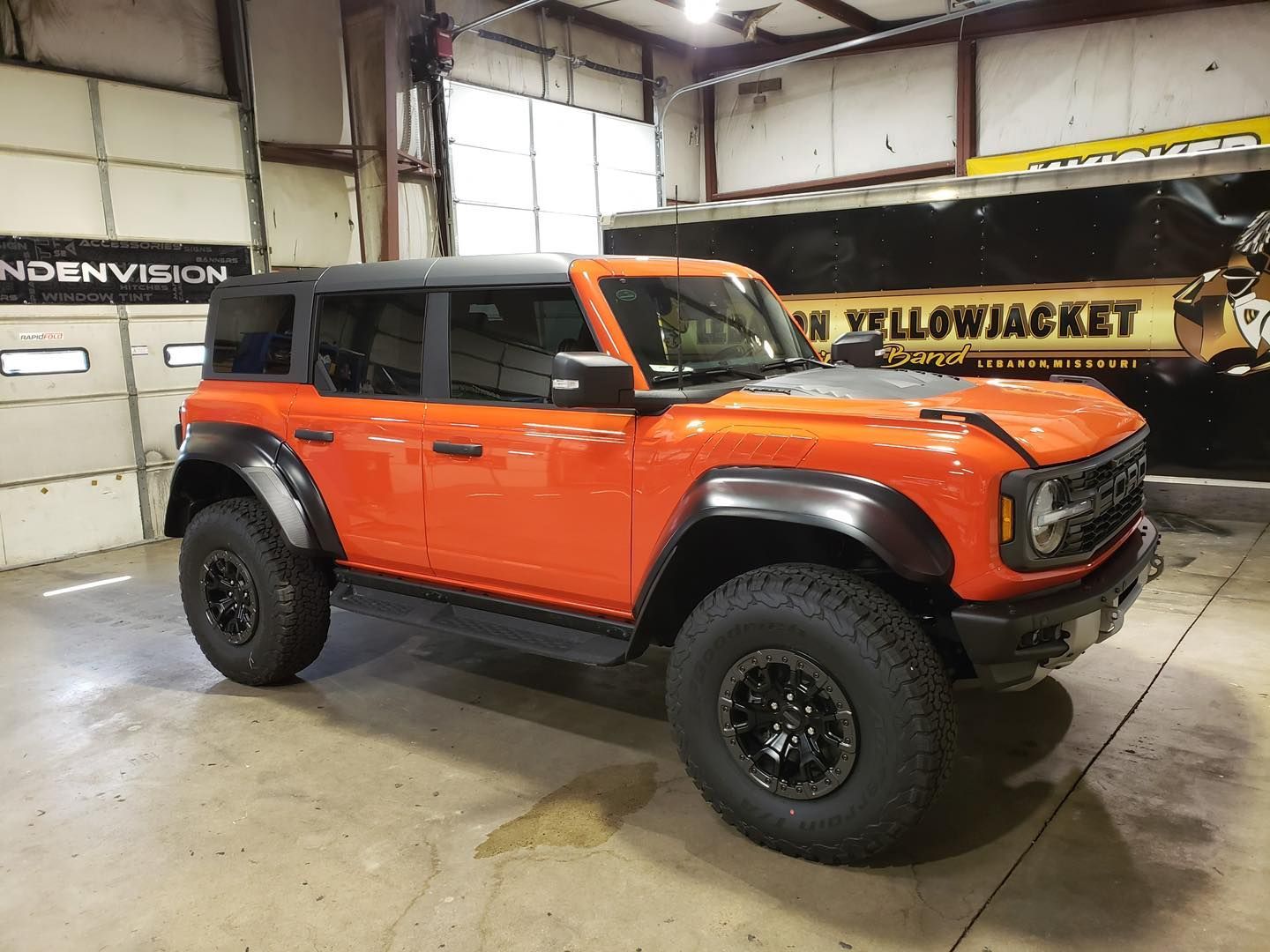 Orange off-road SUV with black roof and wheels parked in a garage