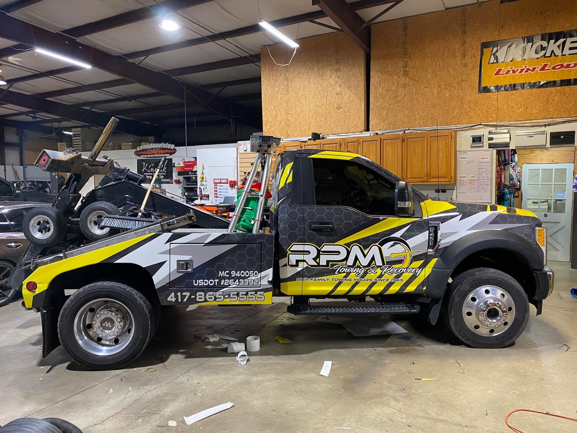 Tow truck with RPM graphics inside an auto shop garage.