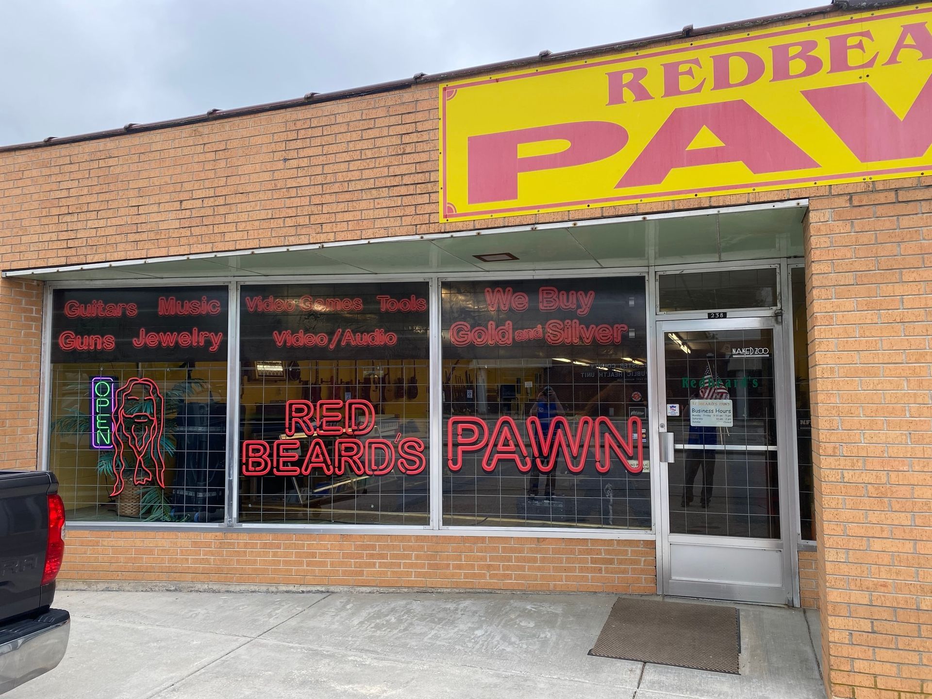 Storefront of Red Beard Pawn with neon signage in a brick strip mall