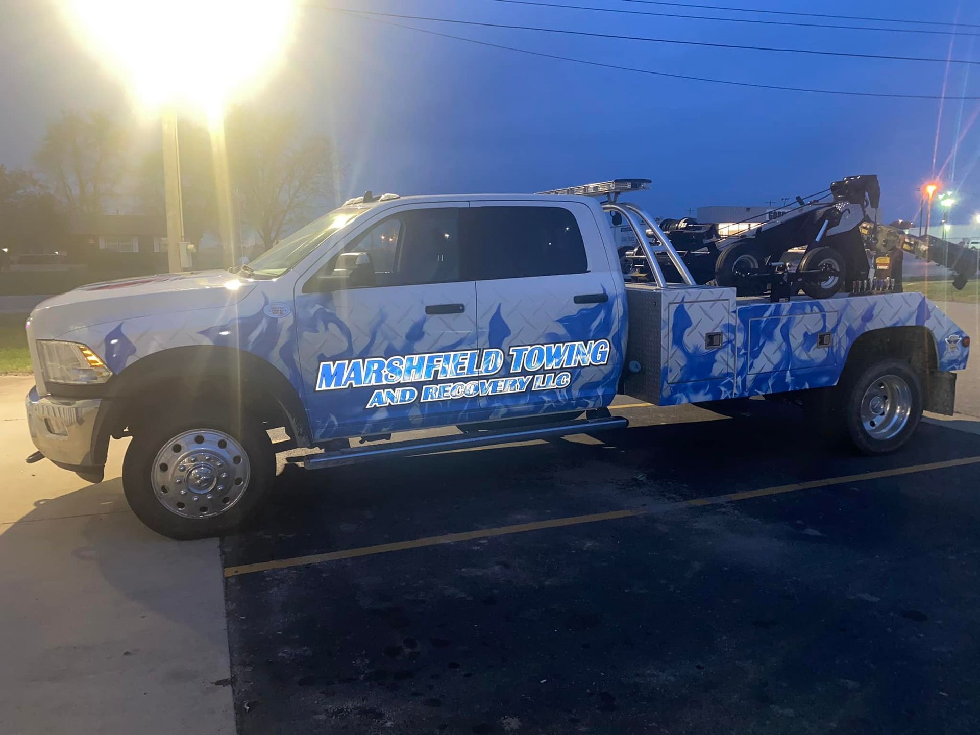 White pickup truck with blue graphics parked at dusk, carrying equipment in the bed