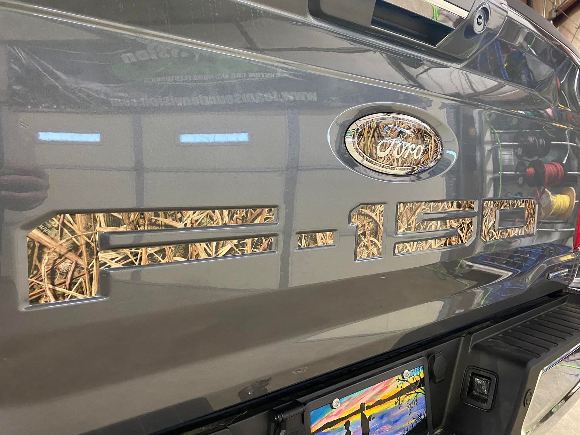 Close-up of a glossy gray car with decorative vents and reflective windows in a showroom-like setting