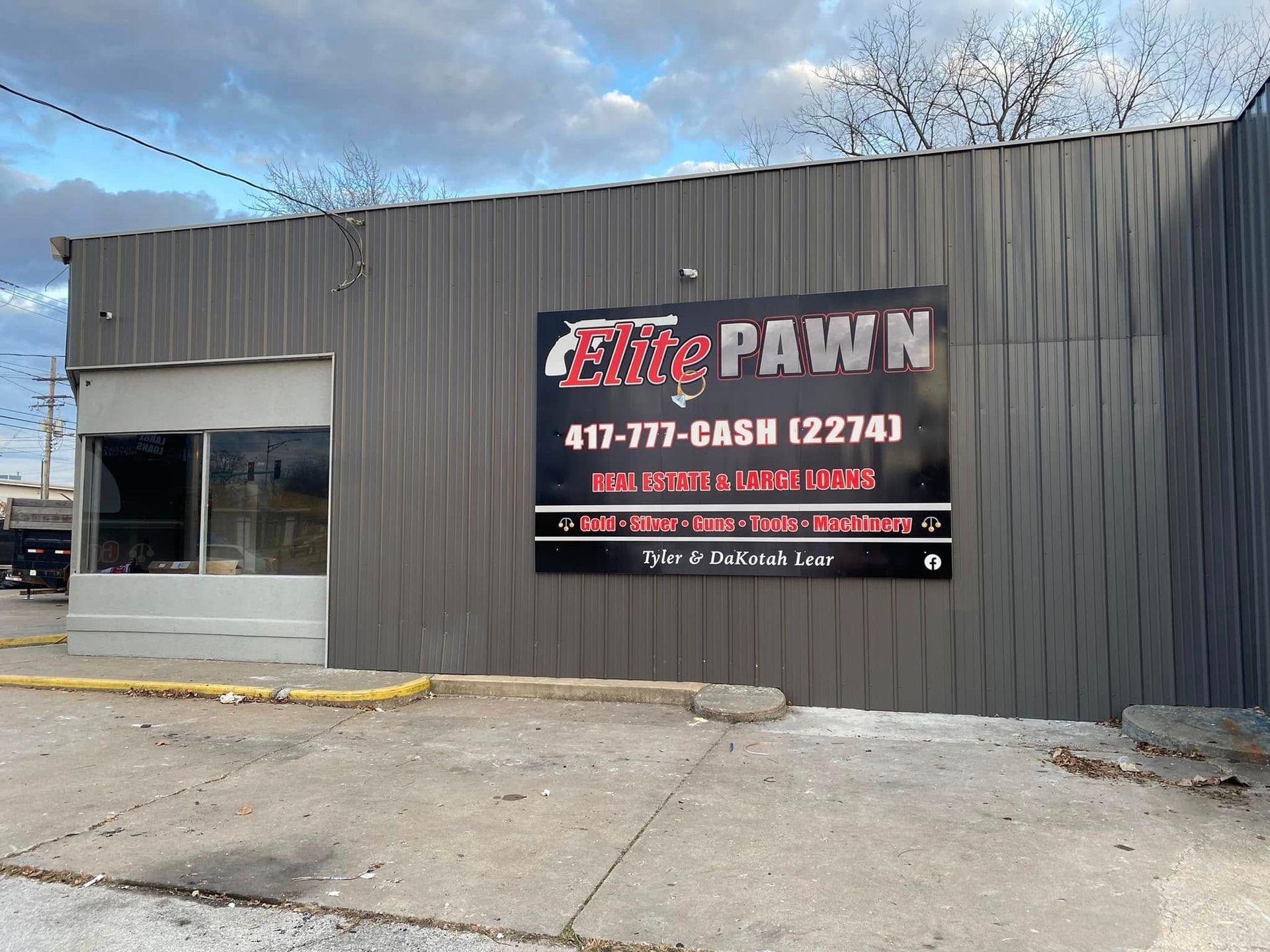 Fire Pawn storefront with gray siding and large red-and-white sign on the facade