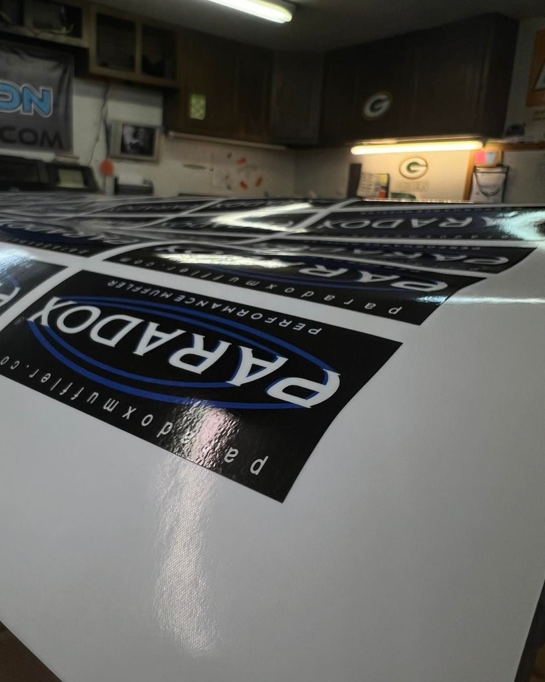 White sheet with black logo decals laid on a workbench in a dim workshop