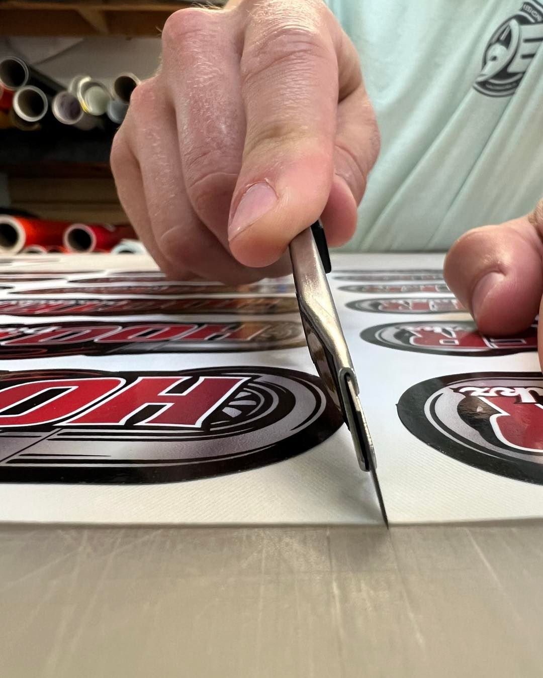 Hands cut sticker decals with a craft knife on a worktable