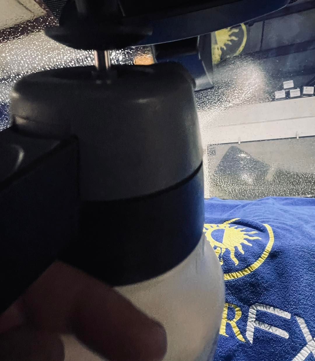 Close-up of a black and white insulated bottle on a desk beside a blue logo mat.