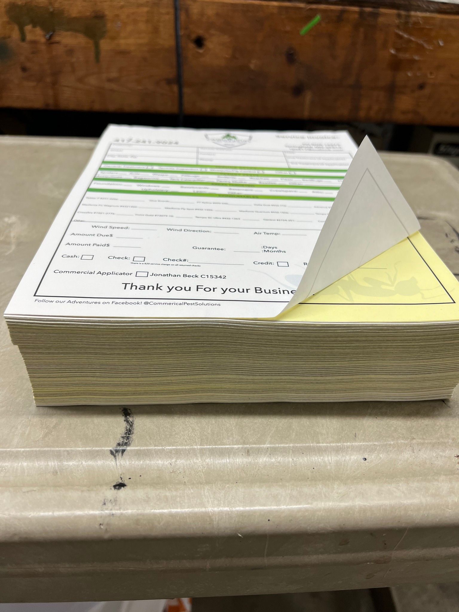 Stack of papers on a table with one page folded into a triangular stand, highlighted in green and yellow.