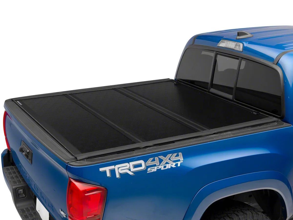 Blue Toyota Tacoma pickup truck with a black tonneau cover, rear side view
