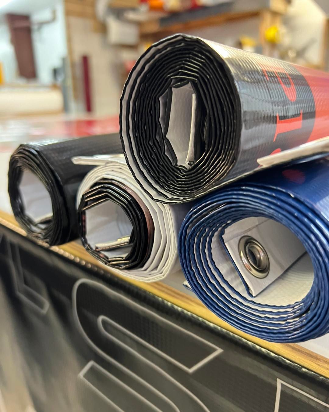 Rolled black, white, and blue mats stacked on a countertop in a store or workshop