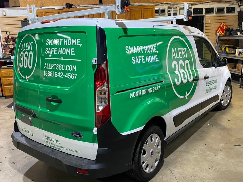 Green-and-white SmartHome Safe Home service van parked indoors, with company branding on the side.
