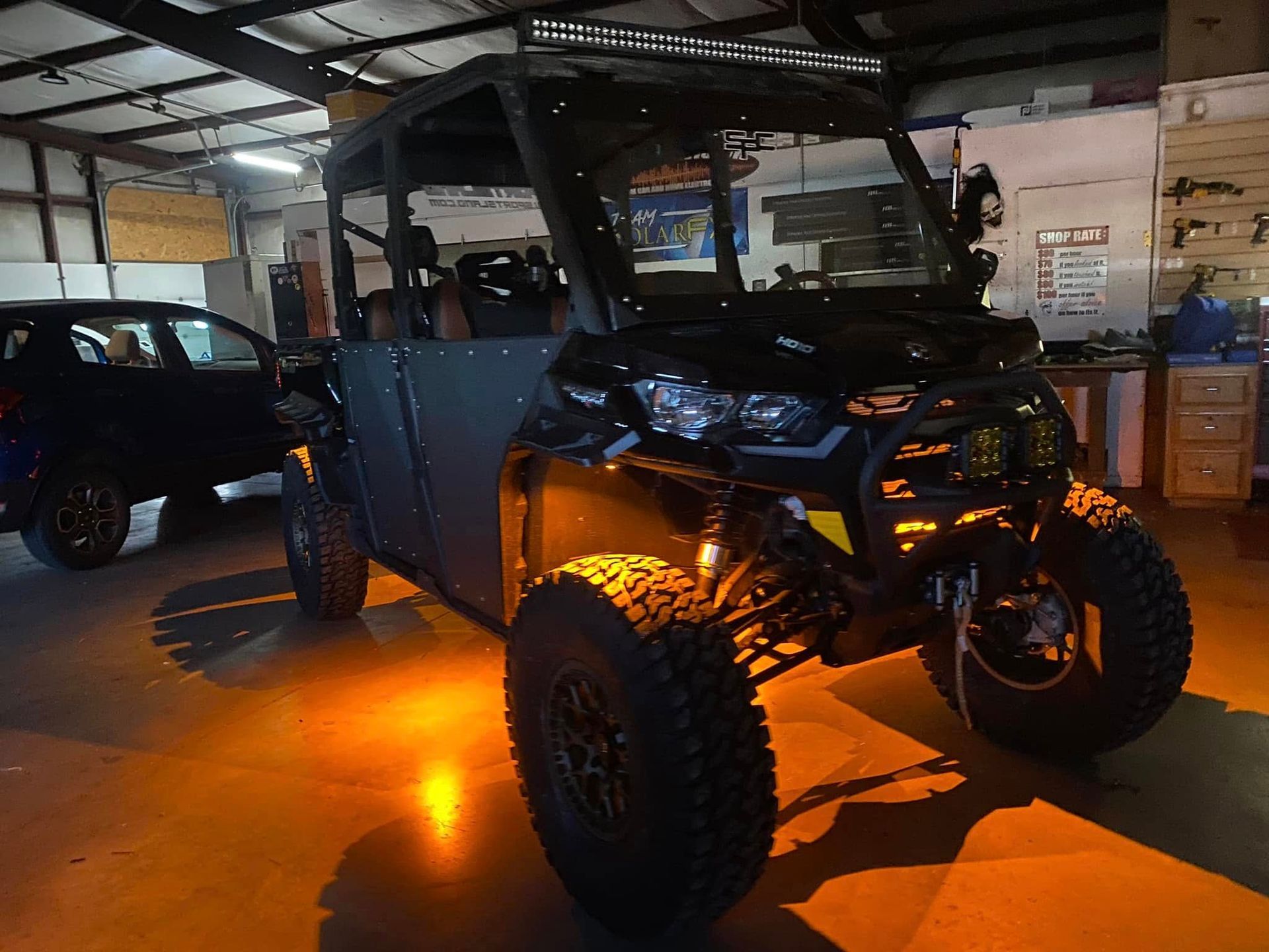 Black off-road ATV with orange underglow lights parked in a garage.