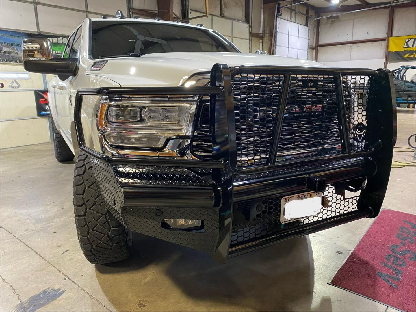 White pickup truck with a black grille guard parked inside a garage