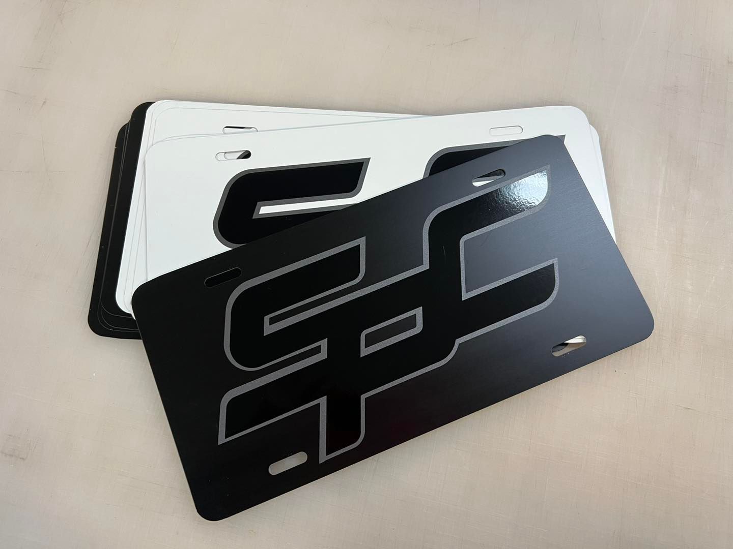 Two black and white rectangular license plates with a stylized geometric cutout design.