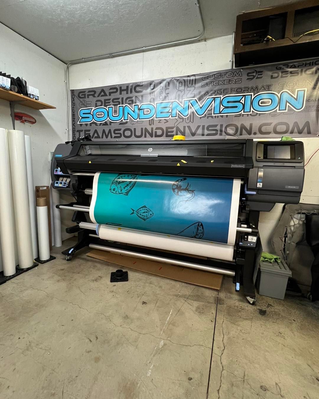 Large printer in a shop printing a blue banner with 