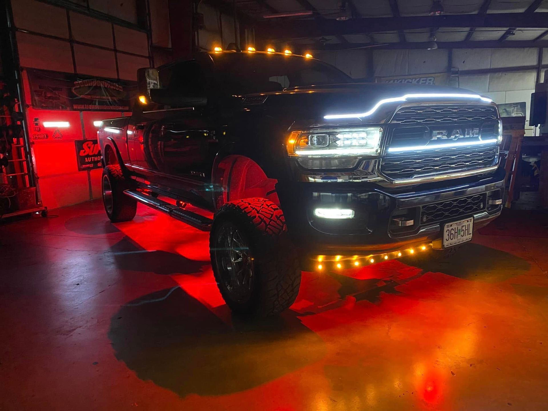 Black lifted truck with bright LED lights and red underglow parked in a garage