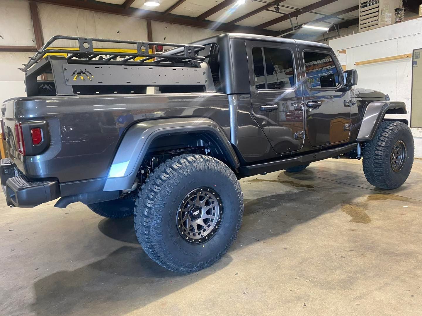 Lifted black pickup truck with off-road tires parked indoors in a garage