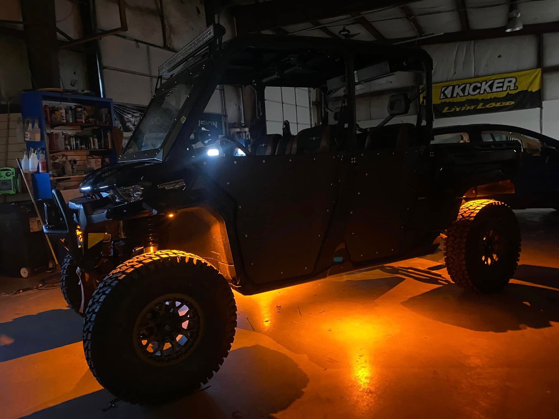 Black off-road truck with bright amber underglow parked in a dark garage
