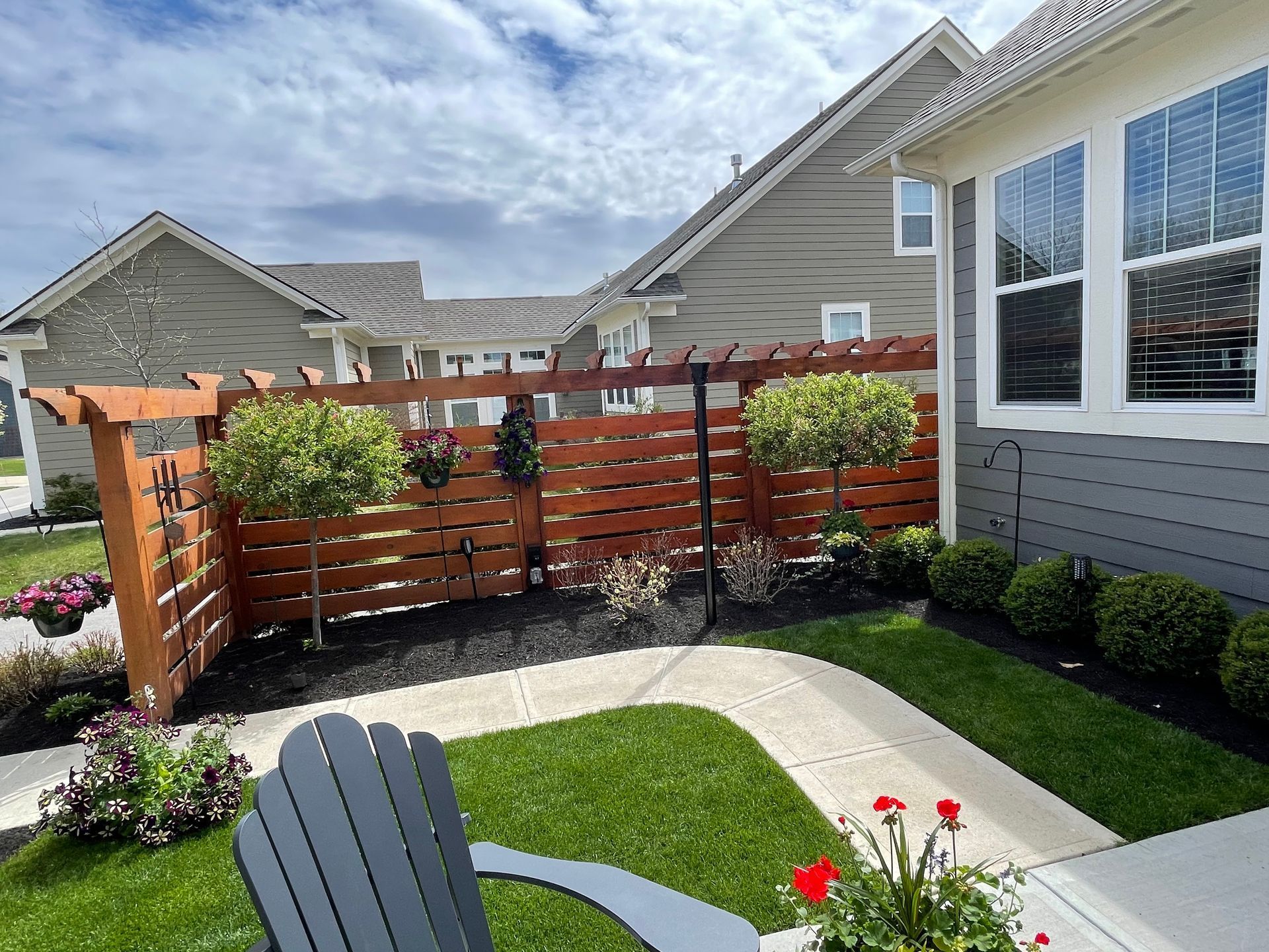 A lawn chair is sitting in front of a house with a wooden fence.