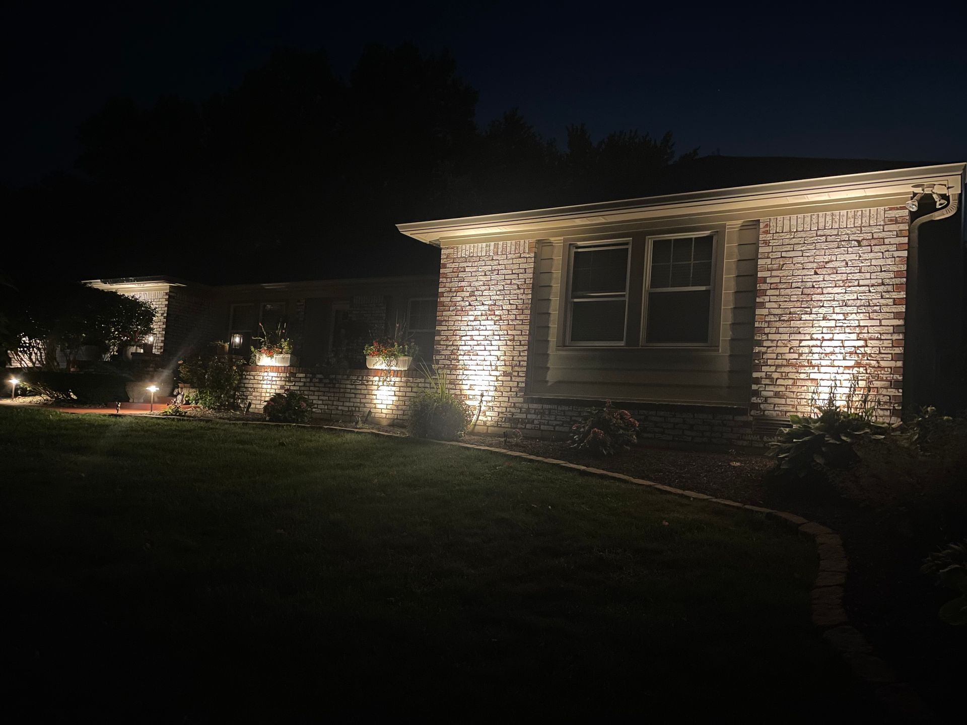 A house is lit up at night with lights on the side of it.
