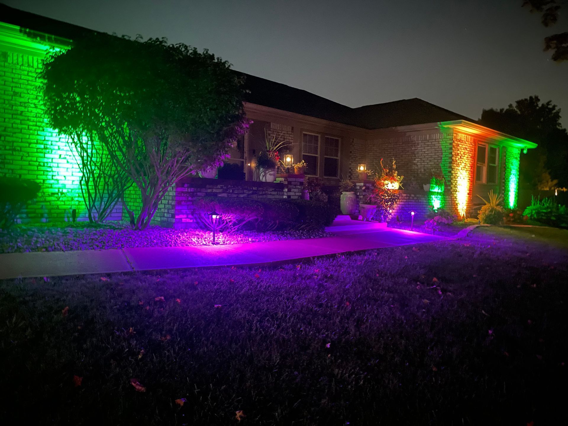 A house is lit up with green and purple lights at night.