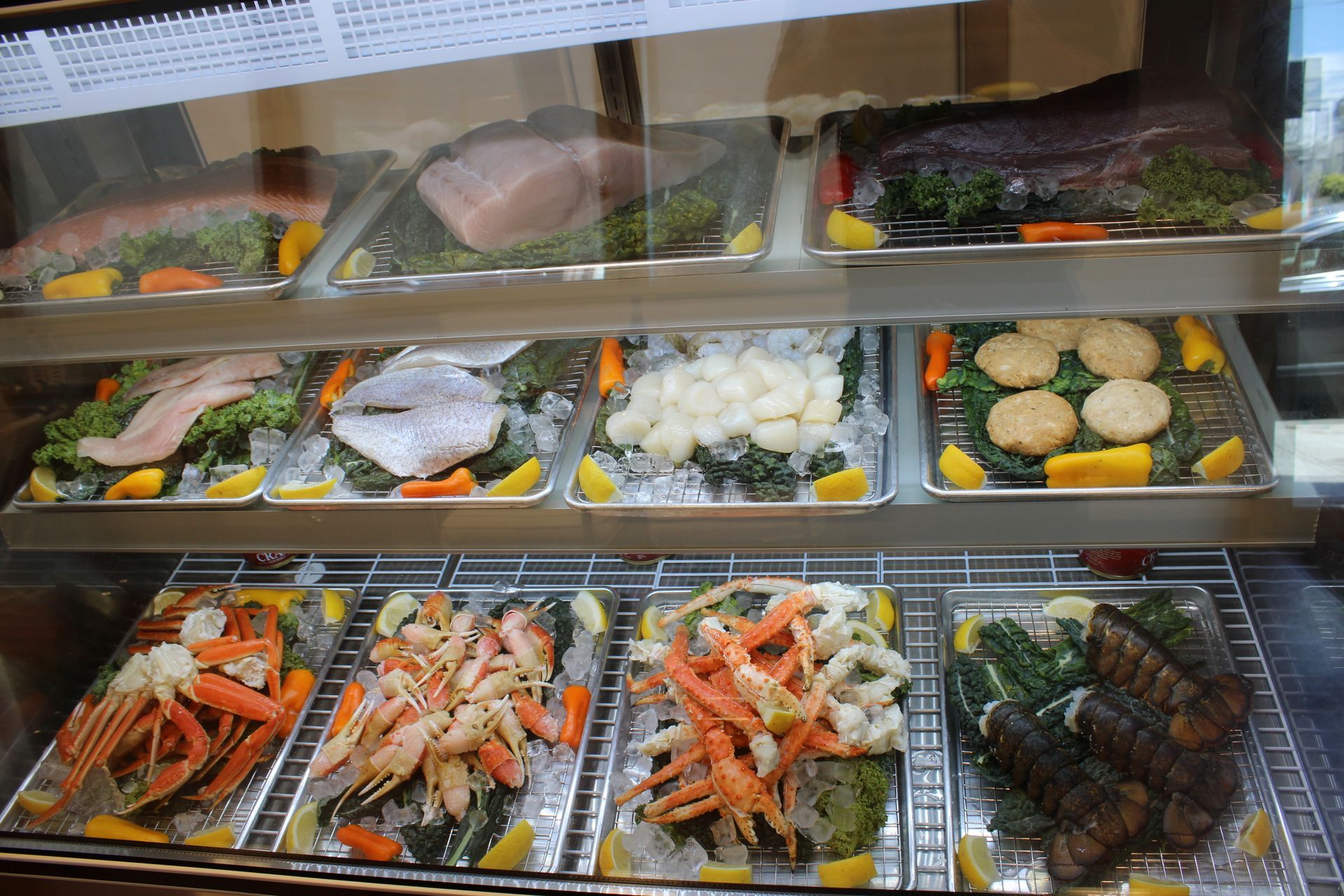 Display case of assorted seafood trays, including shrimp, fish, and shellfish, in a market display.