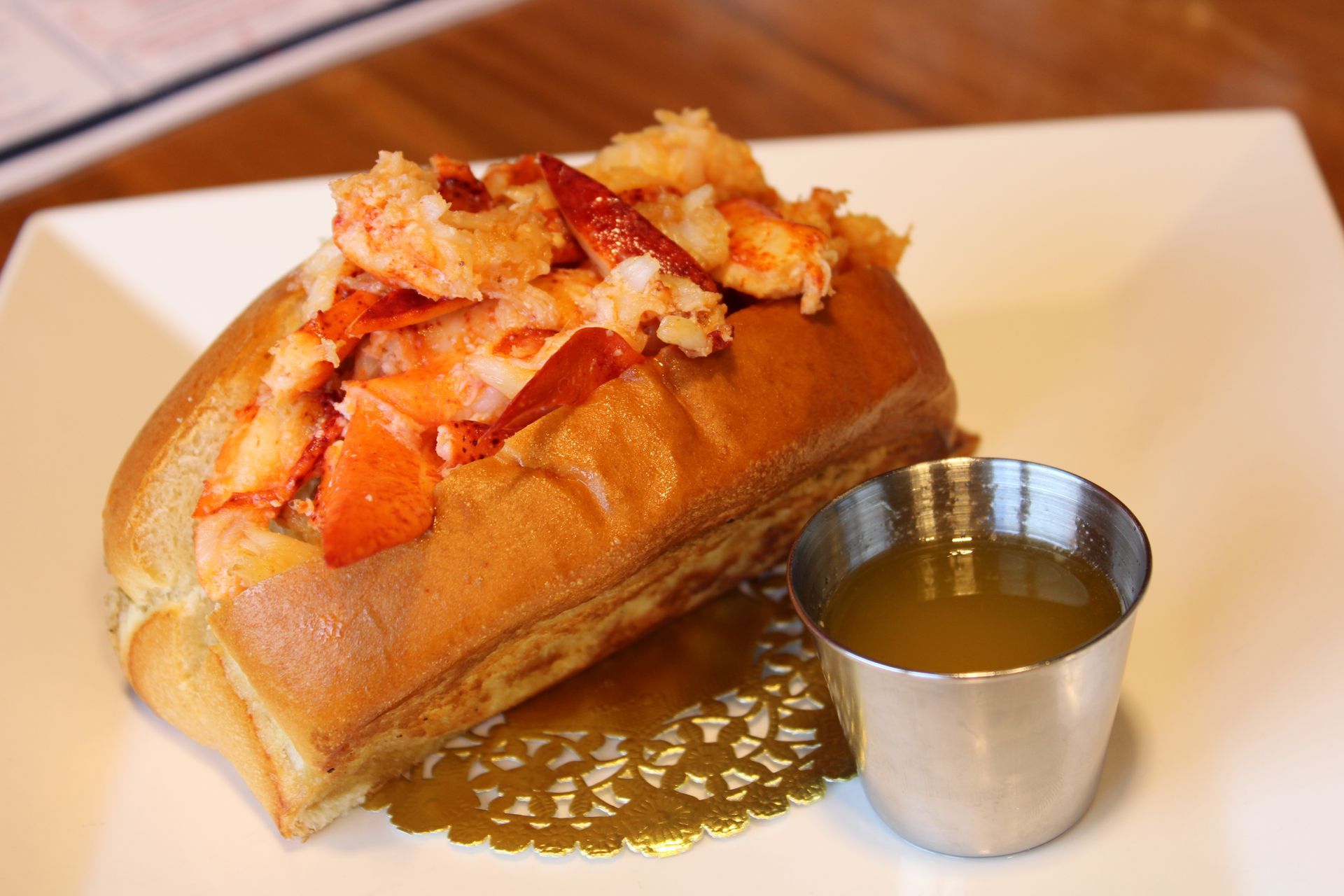 Crab-topped baked pastry on a white plate, with sauce and a blurred dining table in the background