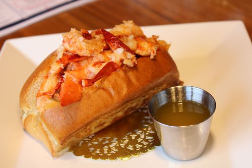 Crab-topped baked pastry on a white plate, with sauce and a blurred dining table in the background