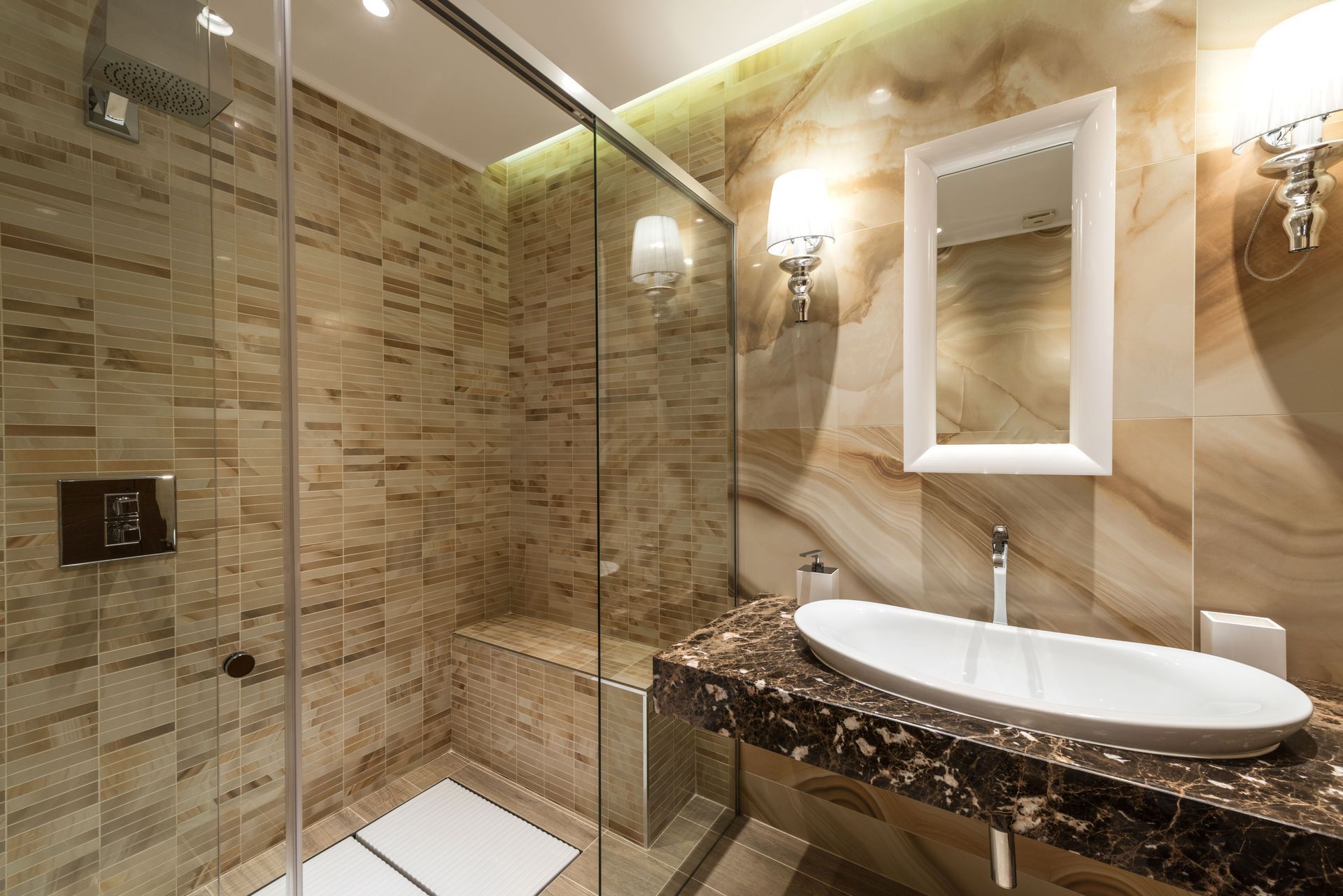 Modern bathroom with glass shower, marble vanity, and wall mirror under warm lighting