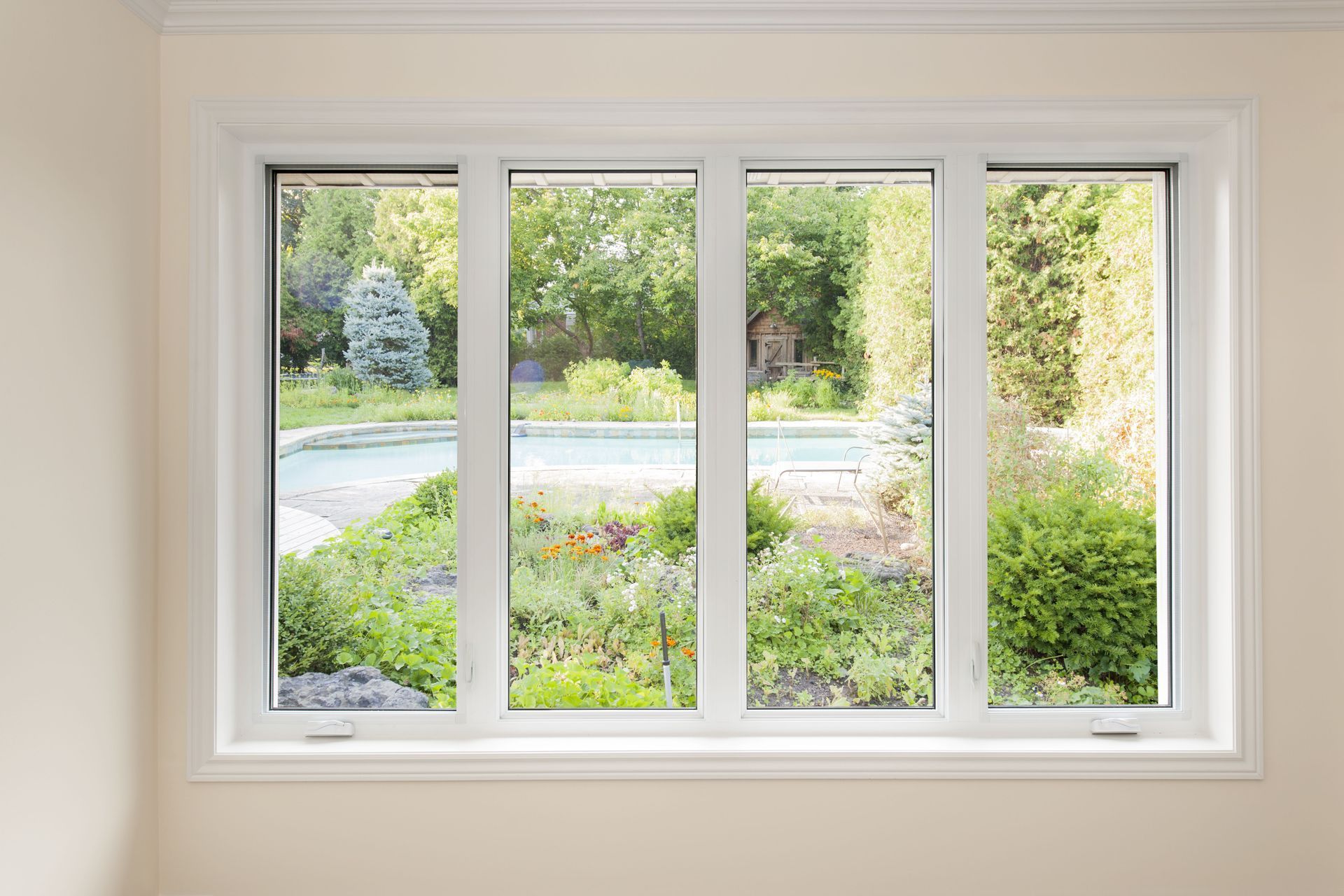 White-framed window overlooking a green garden and curved driveway