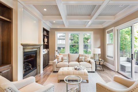 Bright living room with beige sofas, fireplace, large windows, and a coffered ceiling.