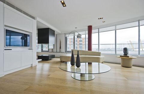 Modern open-plan living room with floor-to-ceiling windows, beige sofa, glass coffee table, and city view