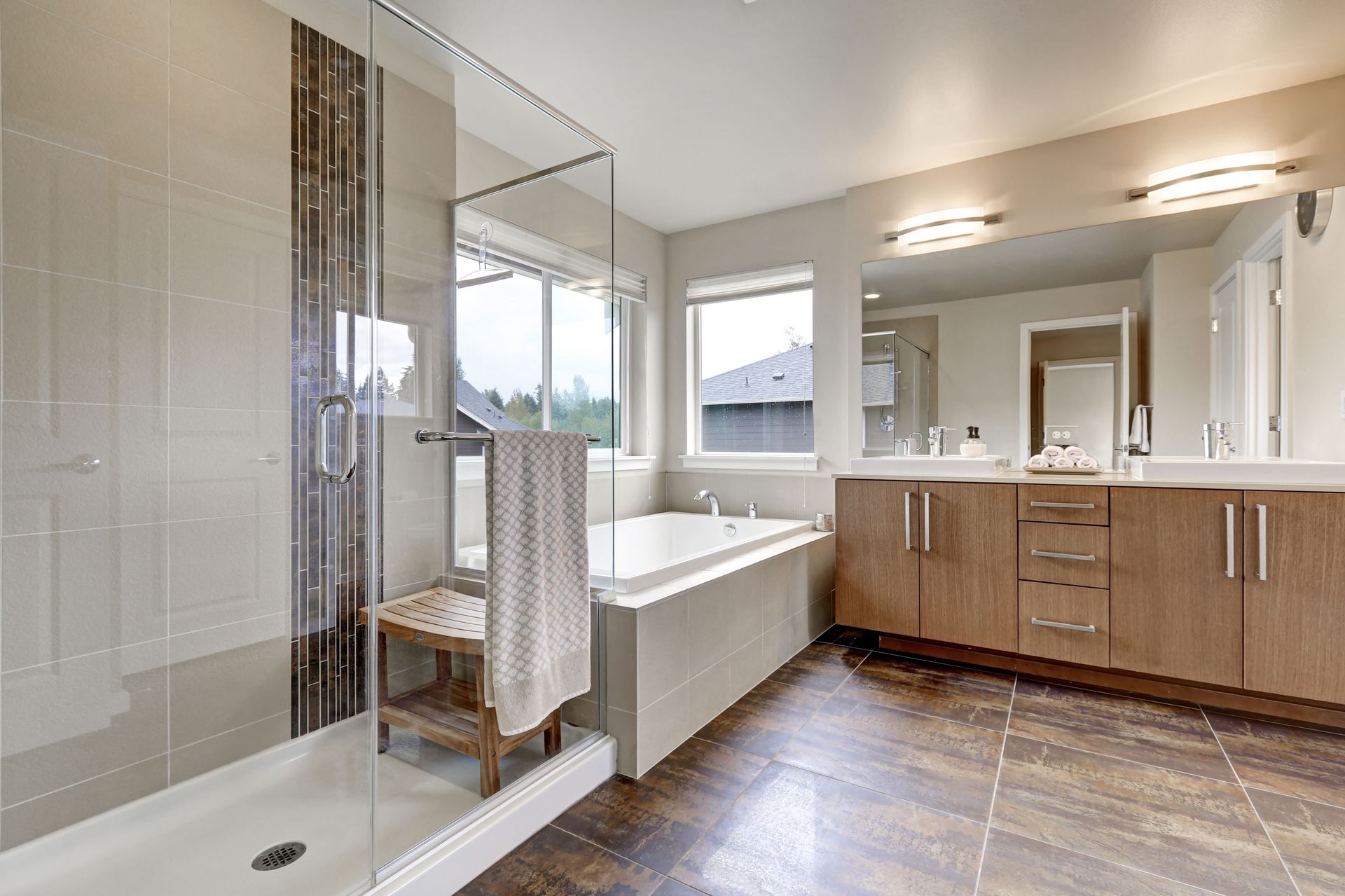 Modern bathroom with glass shower, soaking tub, double vanity, and large mirror