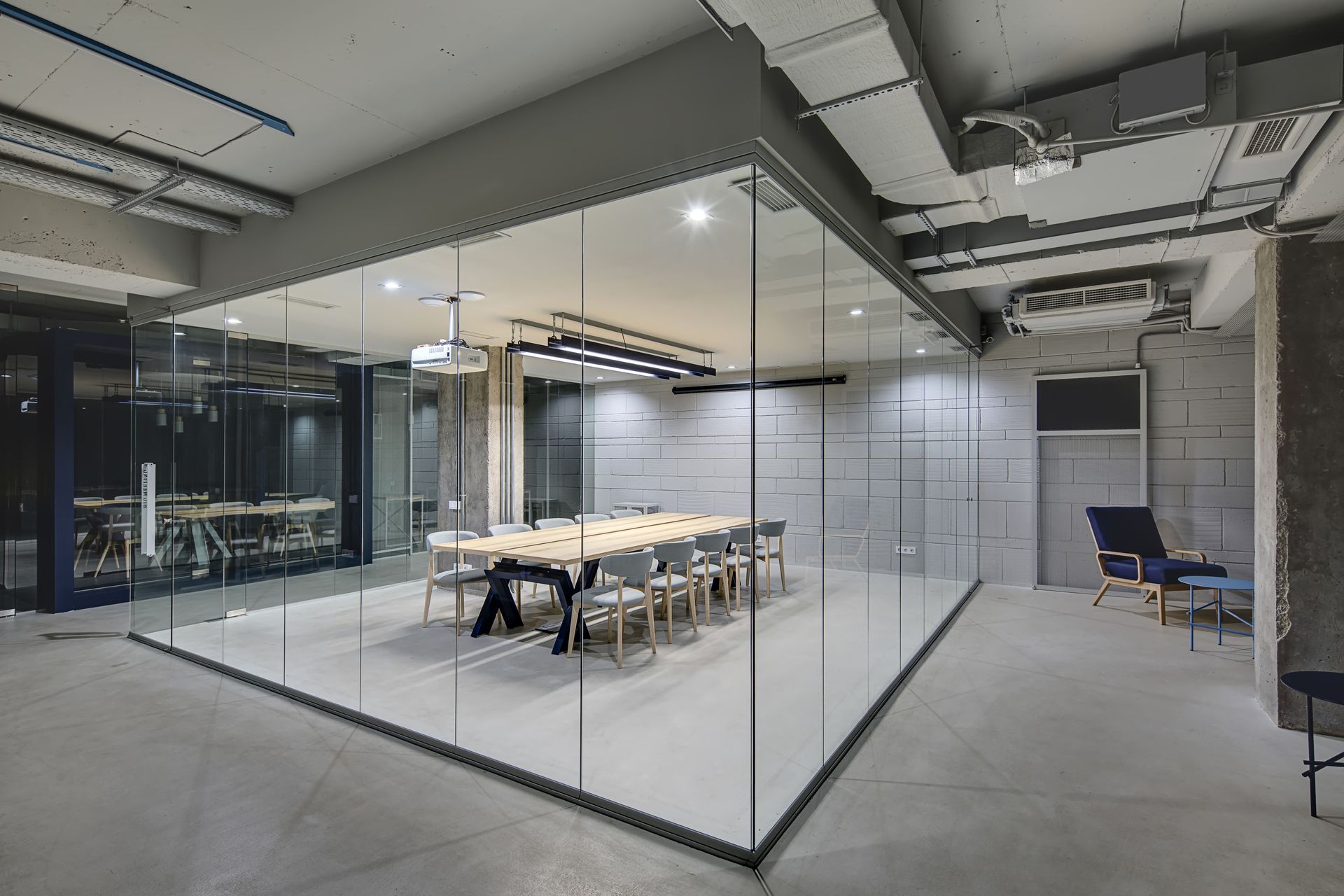 Modern glass-walled conference room with a long table and chairs in an industrial office space