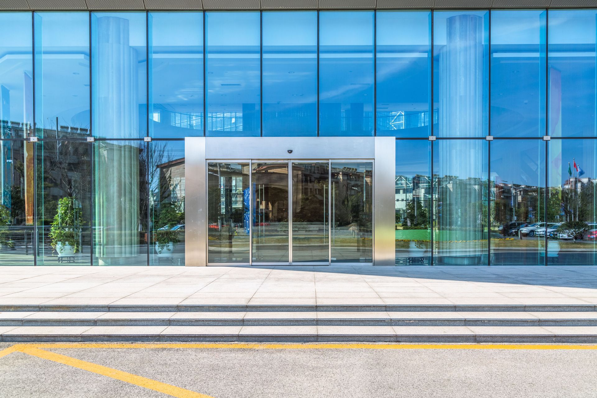 Modern glass office building entrance with sliding doors and blue-tinted windows