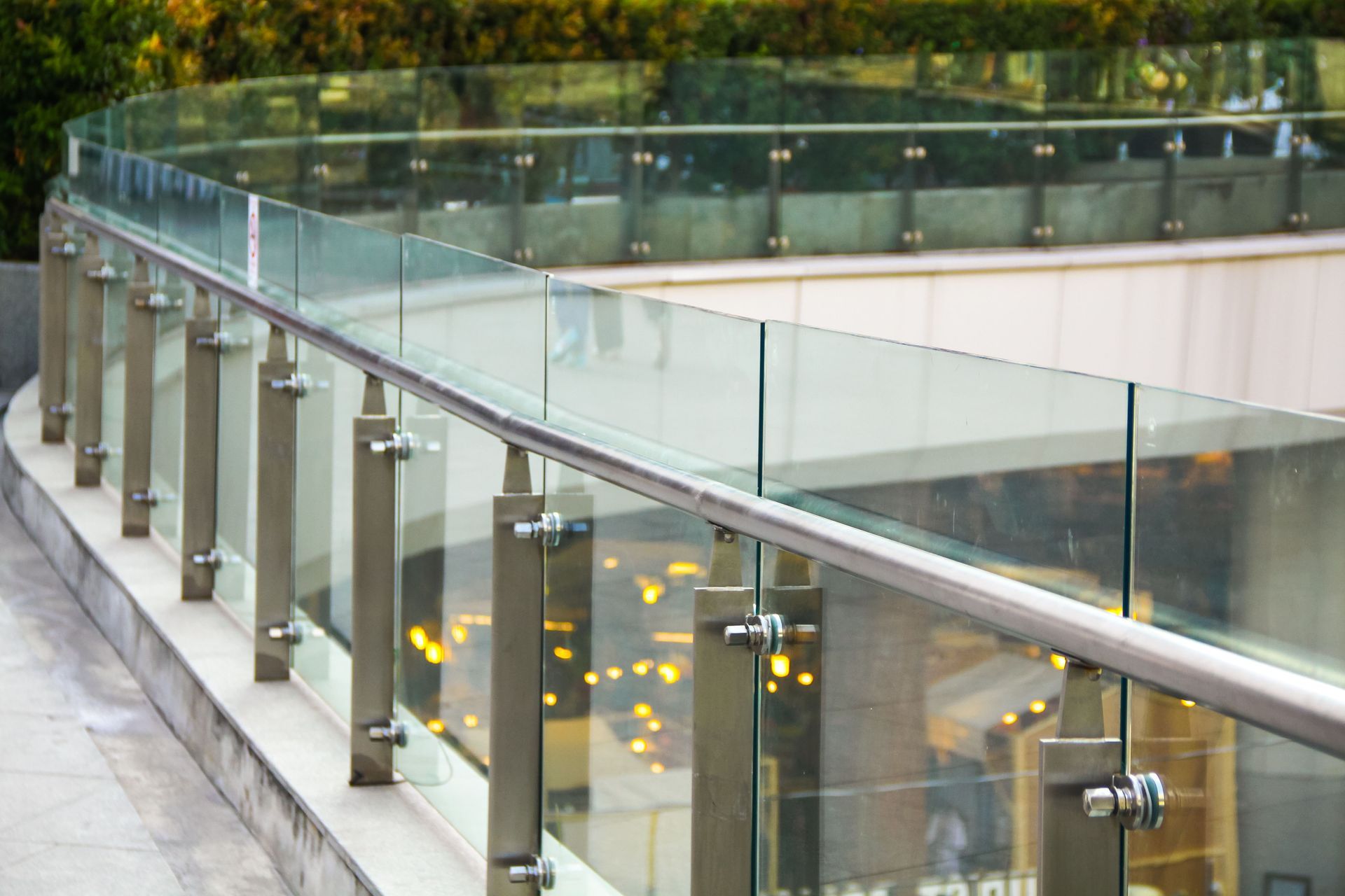 Glass-railed outdoor stairway or terrace with metal posts and warm lights below