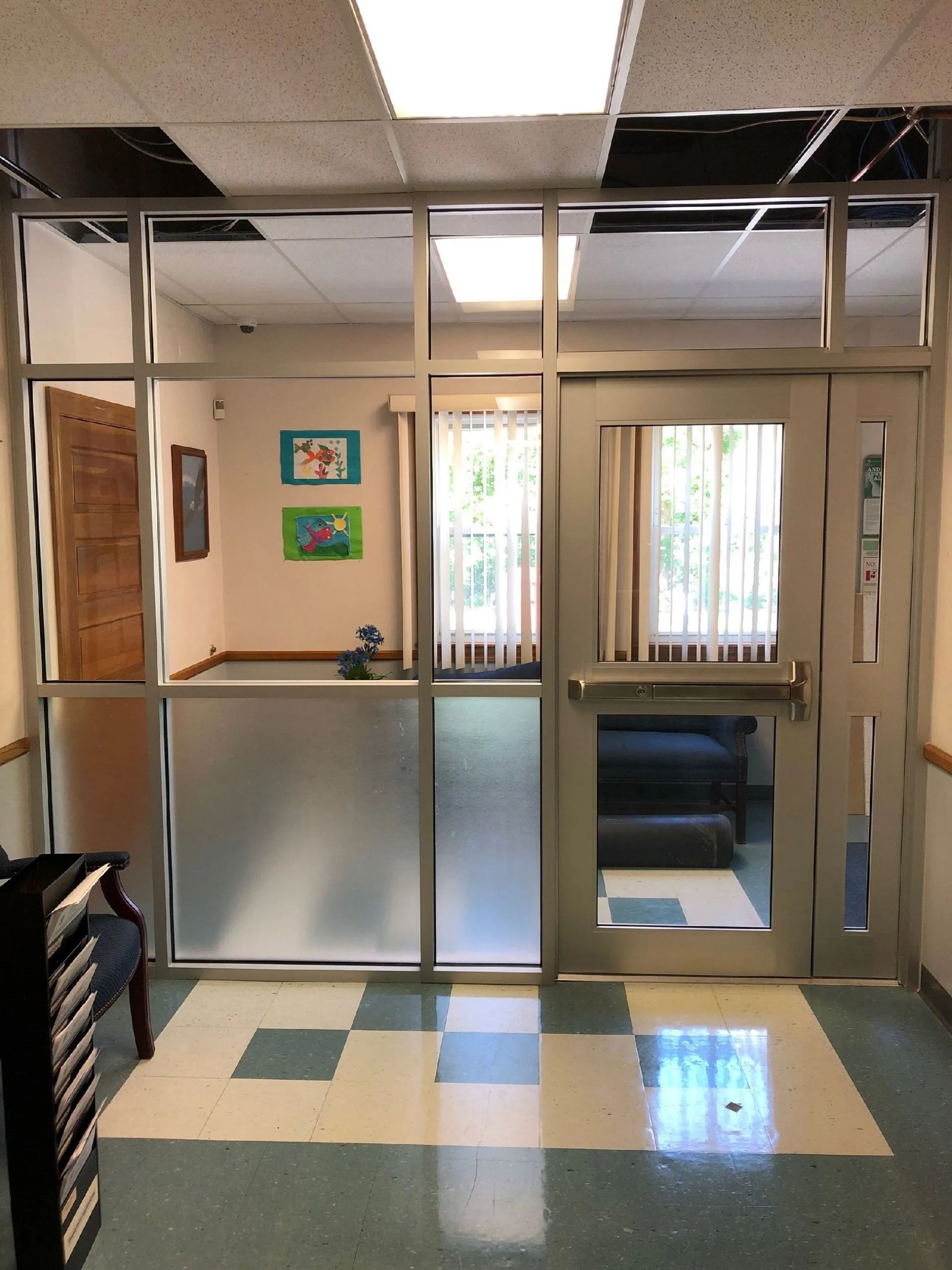 Office lobby with glass partition, open doorway, and checkered floor tiles