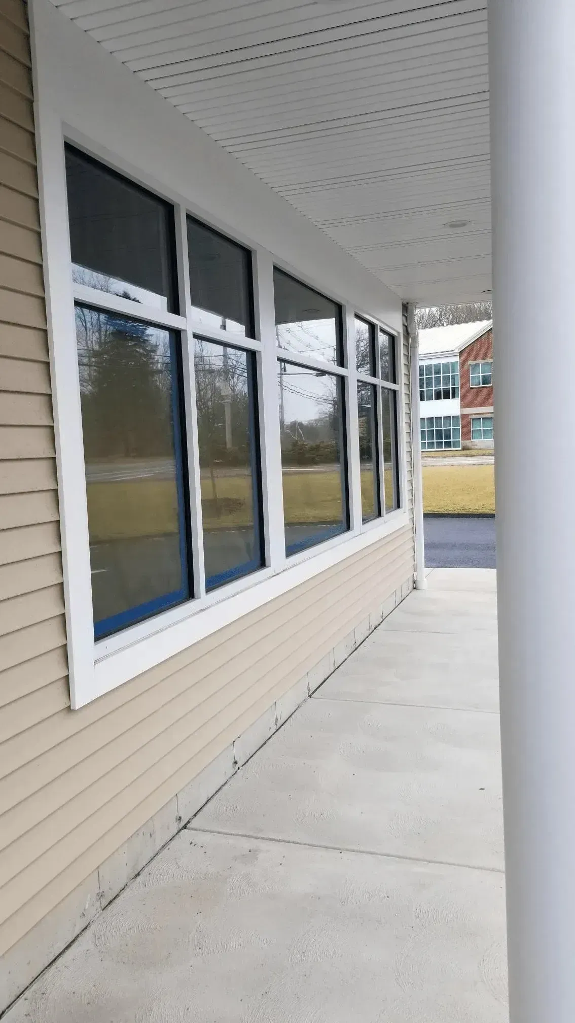 Storefront windows and beige siding along a sidewalk under a covered overhang