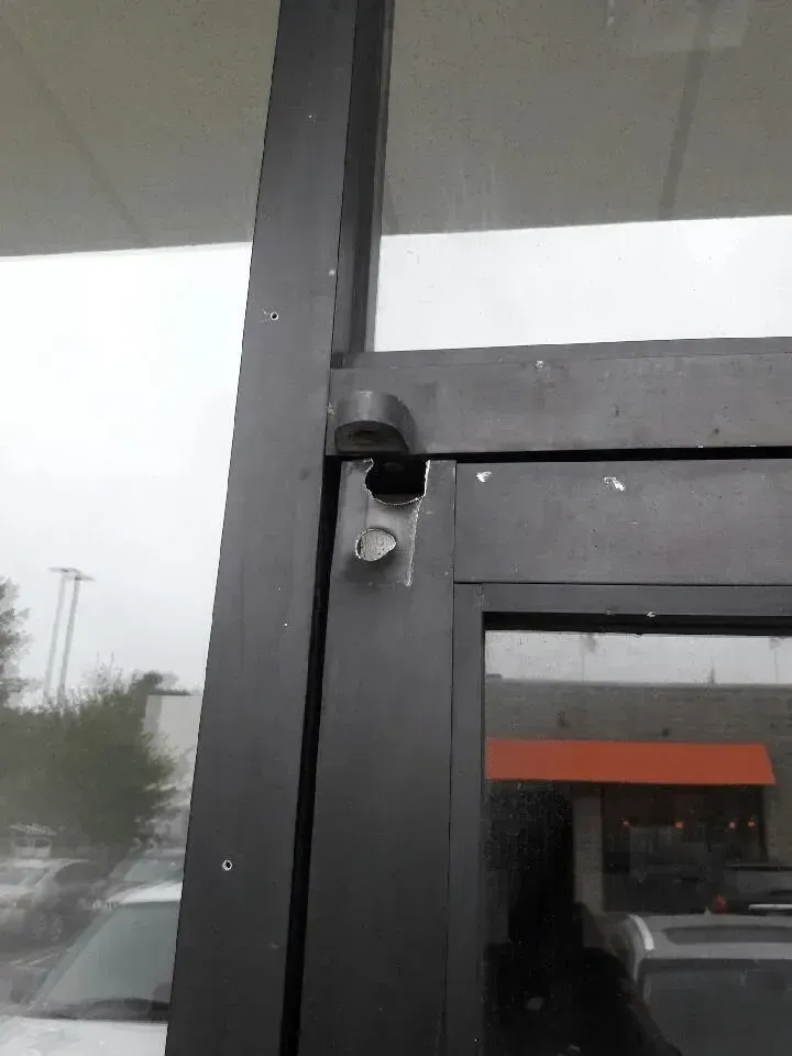 Close-up of a glass door frame with a black security camera mounted beside the entrance.