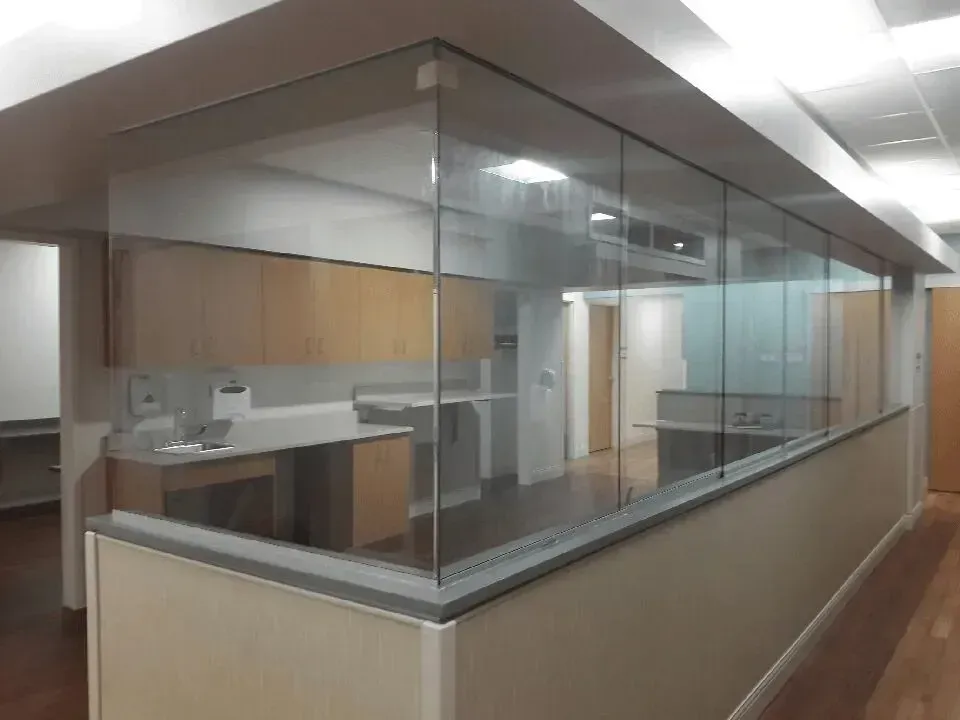 Glass reception desk in a modern office hallway with beige and wood finishes