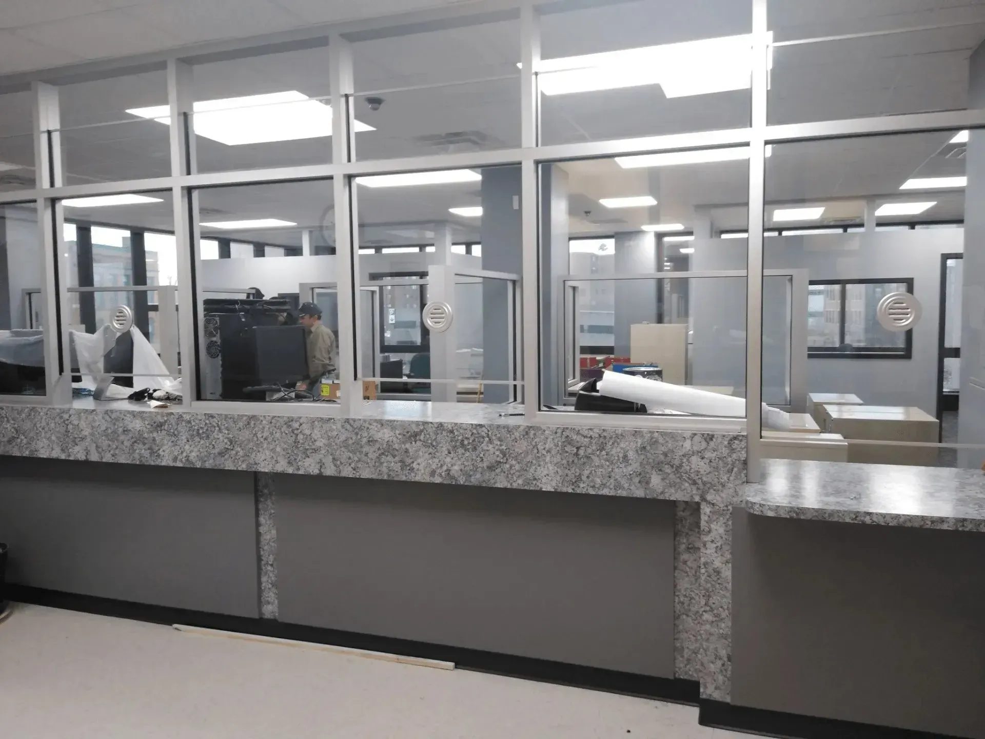Interior view of a service counter with glass windows, gray walls, and fluorescent office lighting