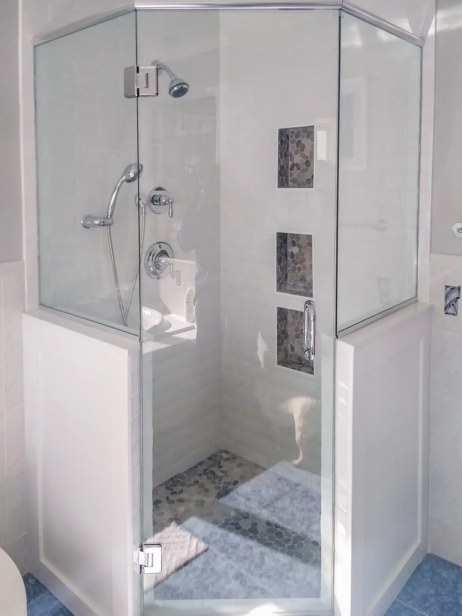 Modern glass shower stall with chrome fixtures and tiled interior