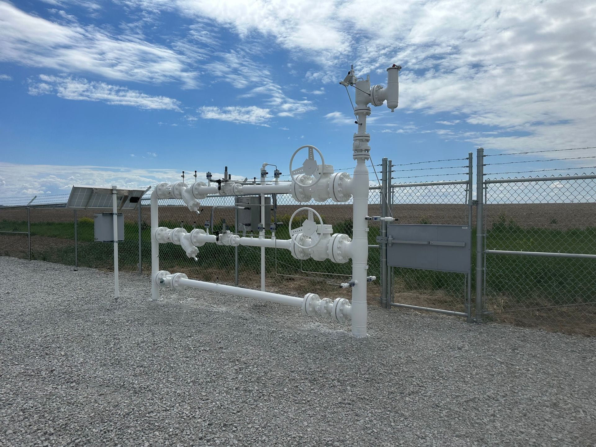 A chain link fence surrounds a row of white pipes.