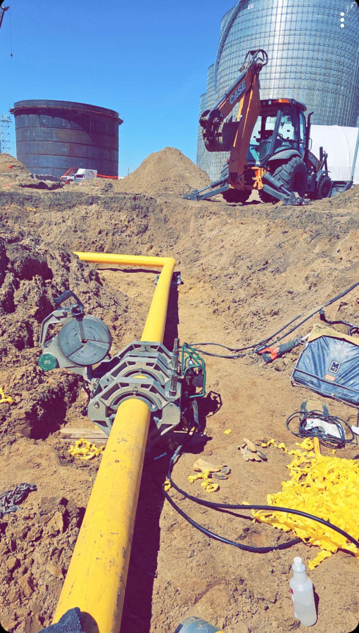 A yellow pipe is sitting in the dirt next to a tractor