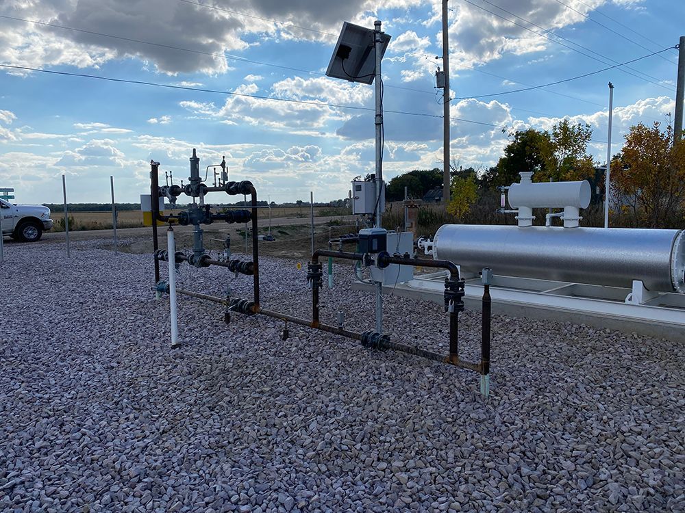 A bunch of pipes are sitting on top of a gravel field