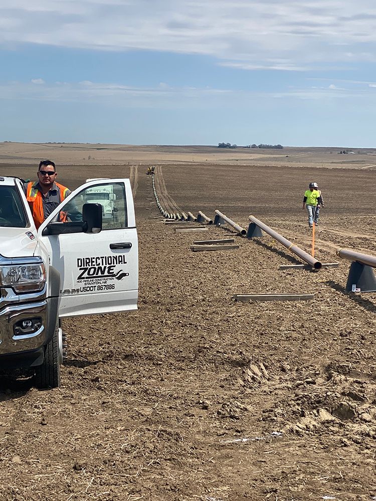 A man is standing next to a truck in the middle of a field