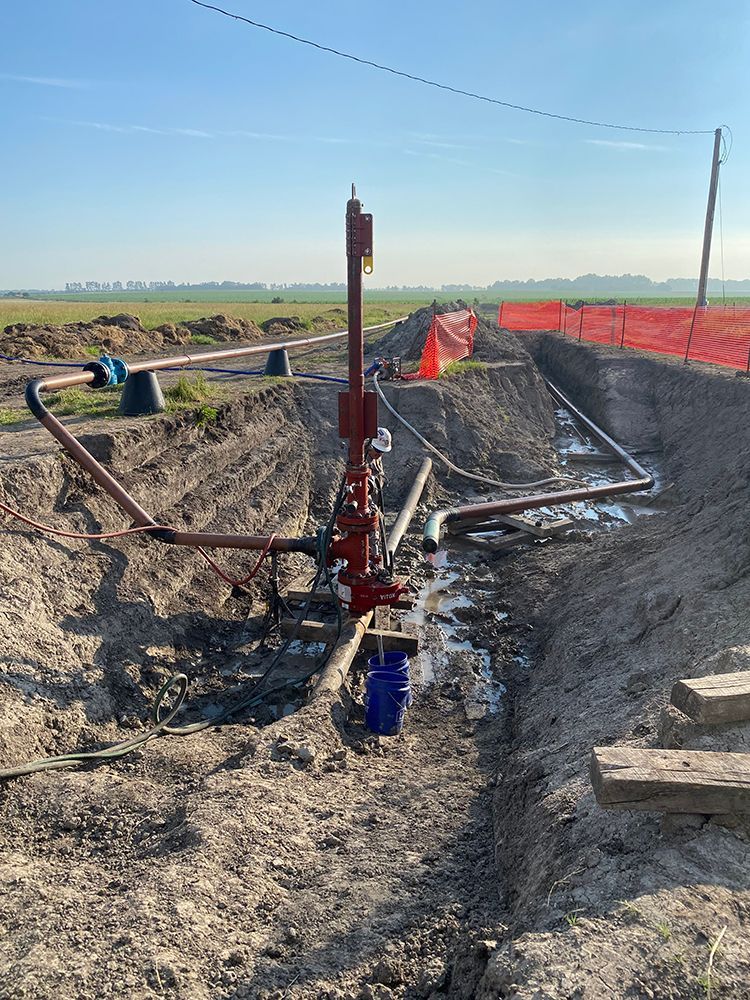 A large pipe is sitting in the middle of a dirt field