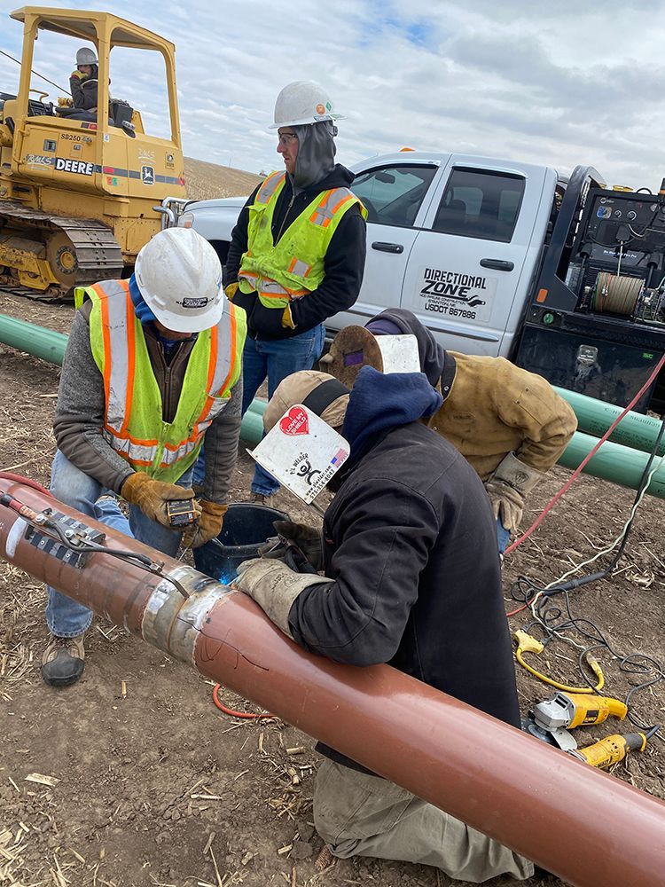 A group of construction workers are working on a pipe