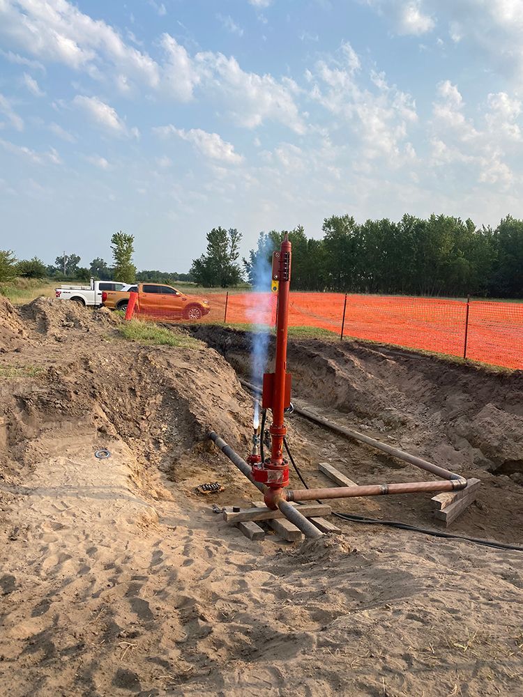 A red pipe is sitting in the middle of a dirt field