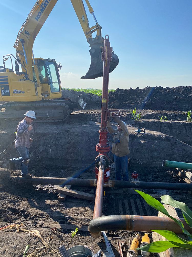 A man is working on a pipe with a yellow excavator